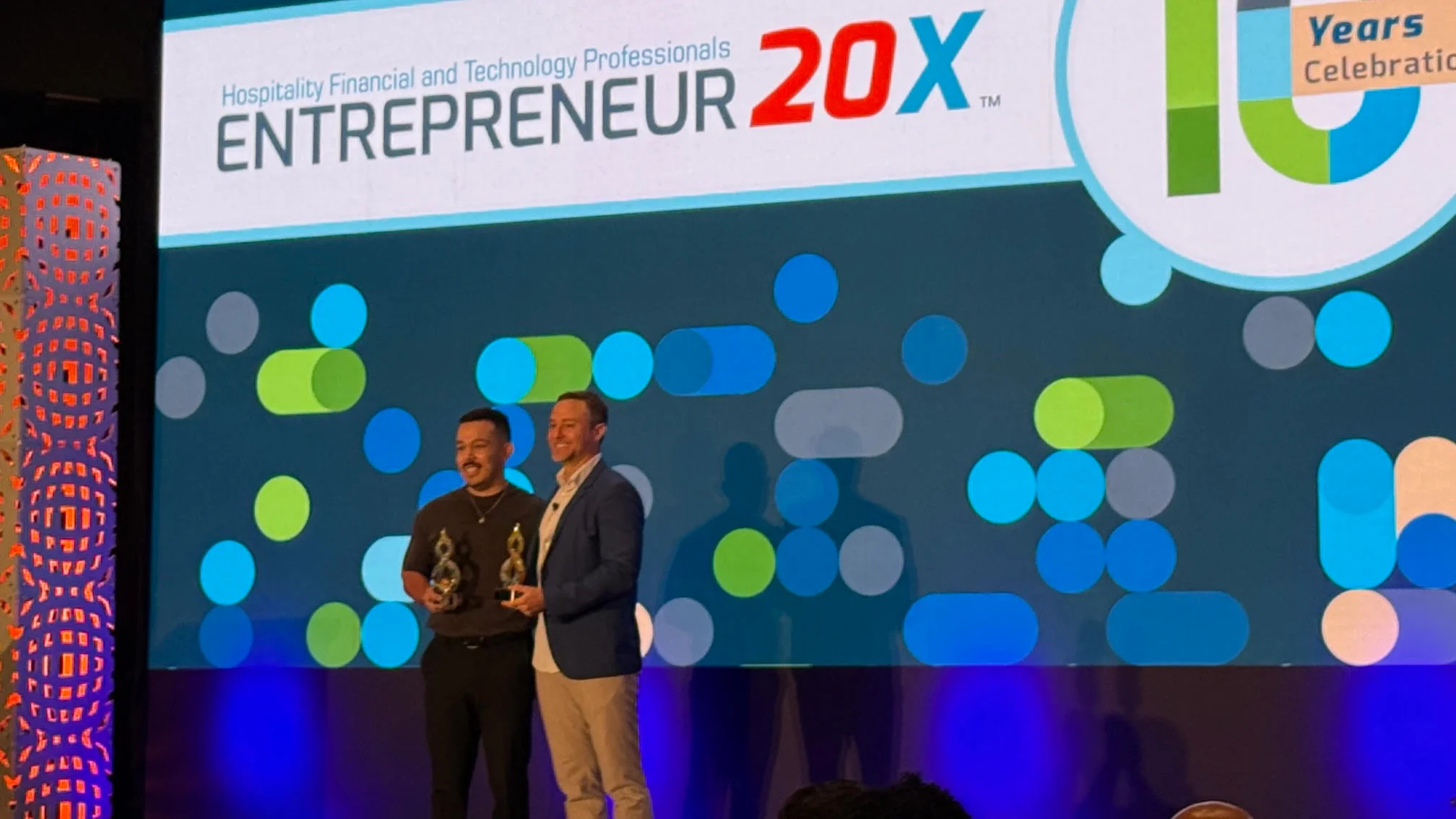 two men standing on a stage holding an award