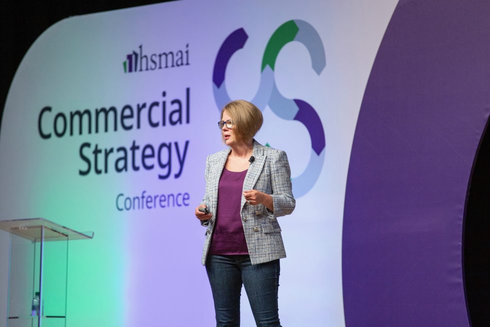 a woman standing on a stage giving a speech